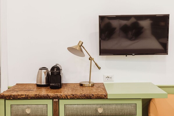 Una kitchenette con cafetera, hervidor y lámpara sobre una encimera de madera.