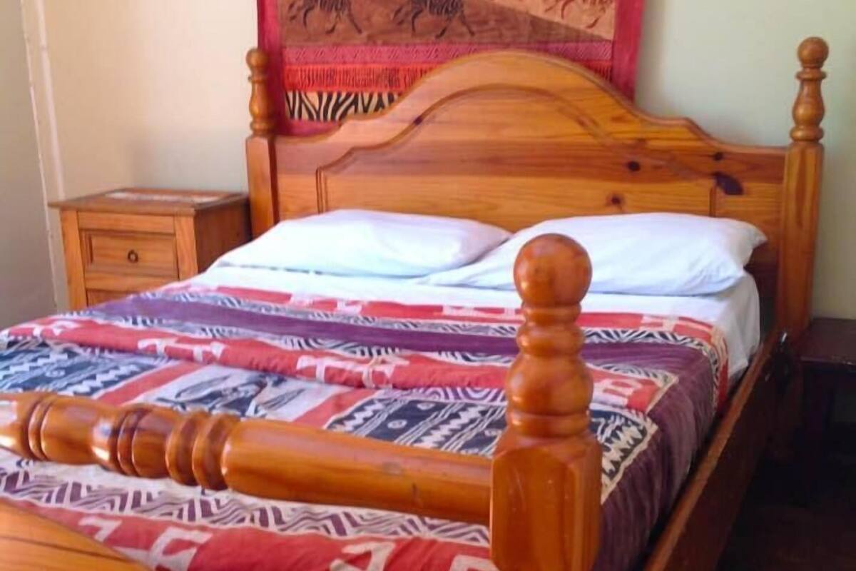 Ein hölzernes Bett mit Kopfteil, einem Nachttisch und einem Wandteppich.