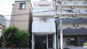 A multi-story residential building with a balcony, a bicycle parked outside, and a utility pole with wires. - Happy Osaka House (Osaka)
