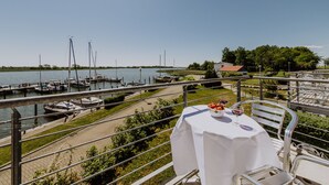 A balcony with a table set for dining, overlooking a marina with boats and a clear sky. - Apartment in the harbor (Puddemin)