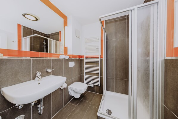 A modern bathroom with a white sink, toilet, and shower.