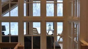 Ein Zimmer mit großen Fenstern, Holzbalken und Blick ins Freie.
