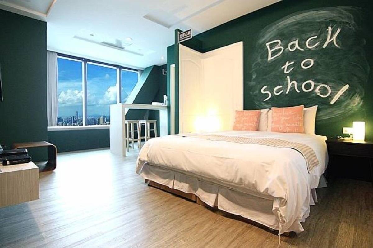 A bedroom with a bed, a desk, a chair, and a large window.