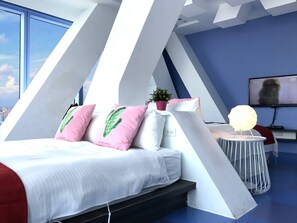 A modern bedroom with a bed, pillows, a small table, a plant, and a TV. - San Jo Hostel (Kaohsiung)