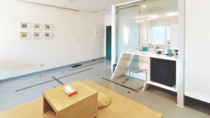 Un espacio de oficina moderno con una amplia mesa de reuniones, un separador de vidrio y una zona de cocina.