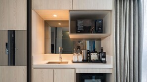Eine kompakte Küchenzeile mit eingebauter Mikrowelle, Kaffeemaschine und einem kleinen Kühlschrank.
