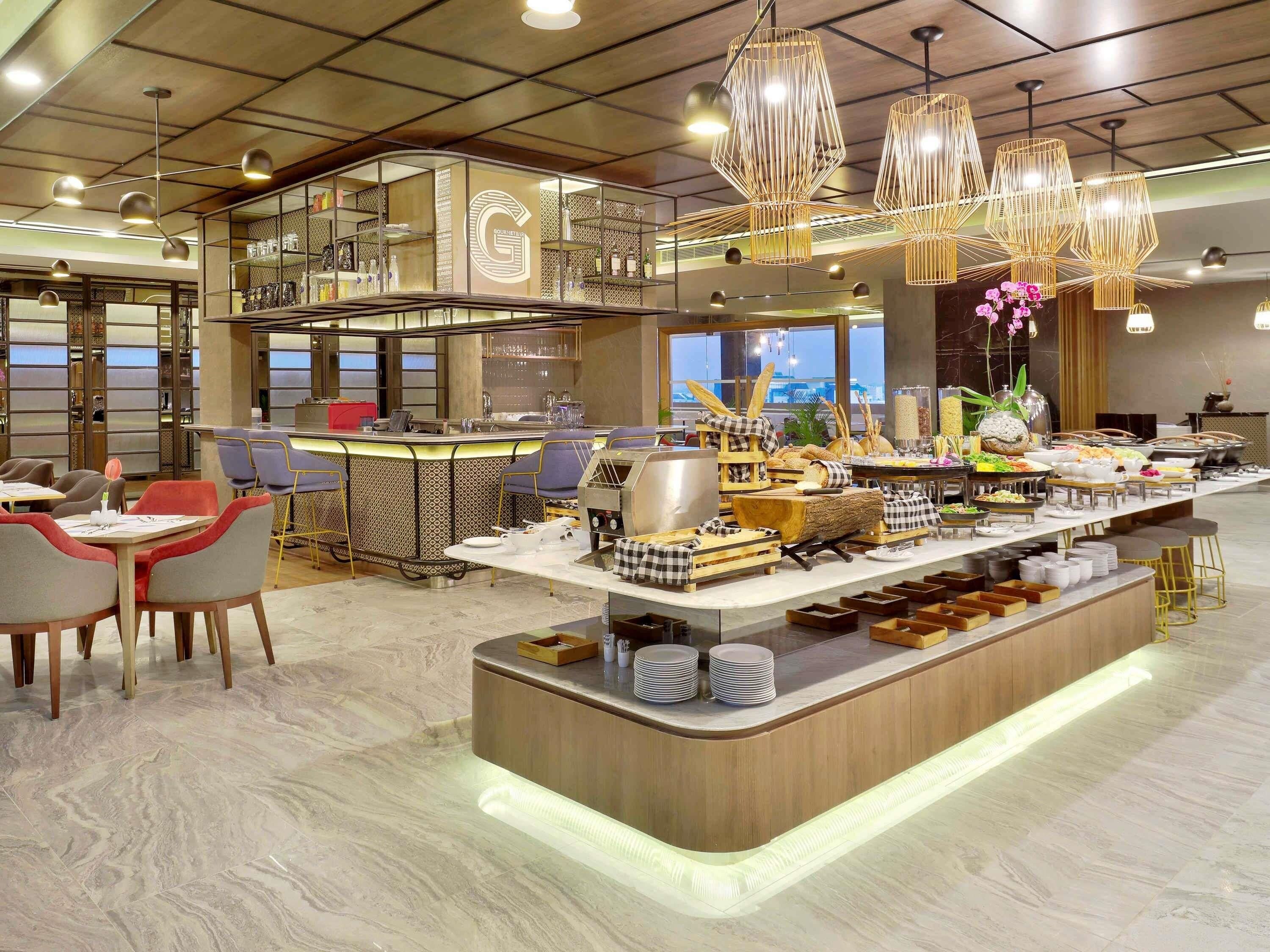 A modern restaurant with a central island, bar seating, and a view of the city.