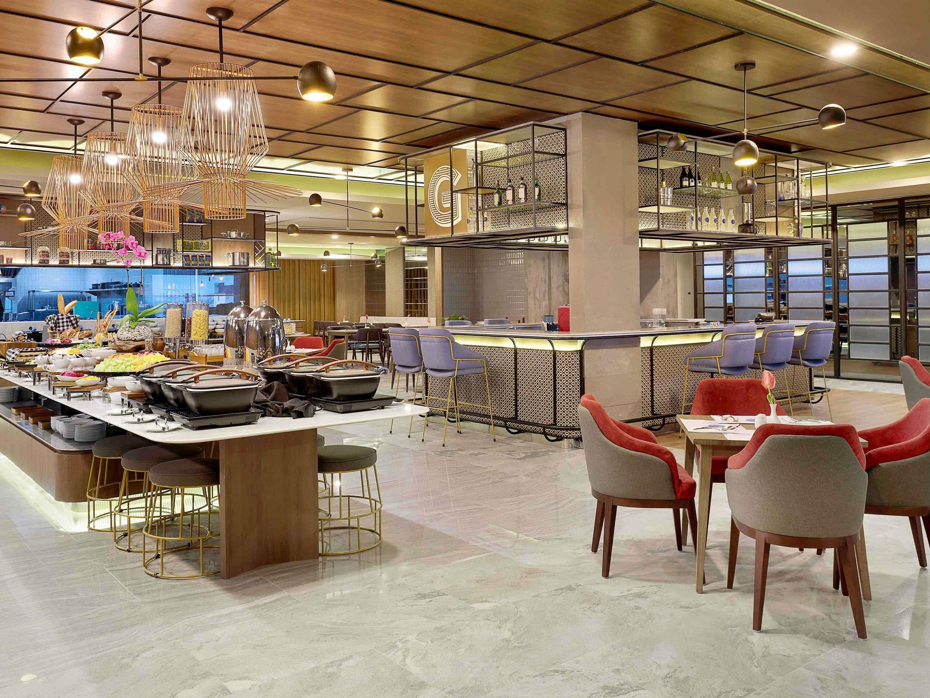 Un restaurant moderne doté d’un bar, d’un espace pour s ’asseoir et d’un buffet.