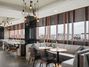 Ein modernes Interieur mit Sitzgelegenheiten, Tischen und hängenden Leuchten.
