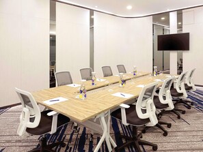 A conference room with a long table, chairs, a TV, and a carpeted floor. - Novotel Suites Yogyakarta Malioboro (Yogyakarta)