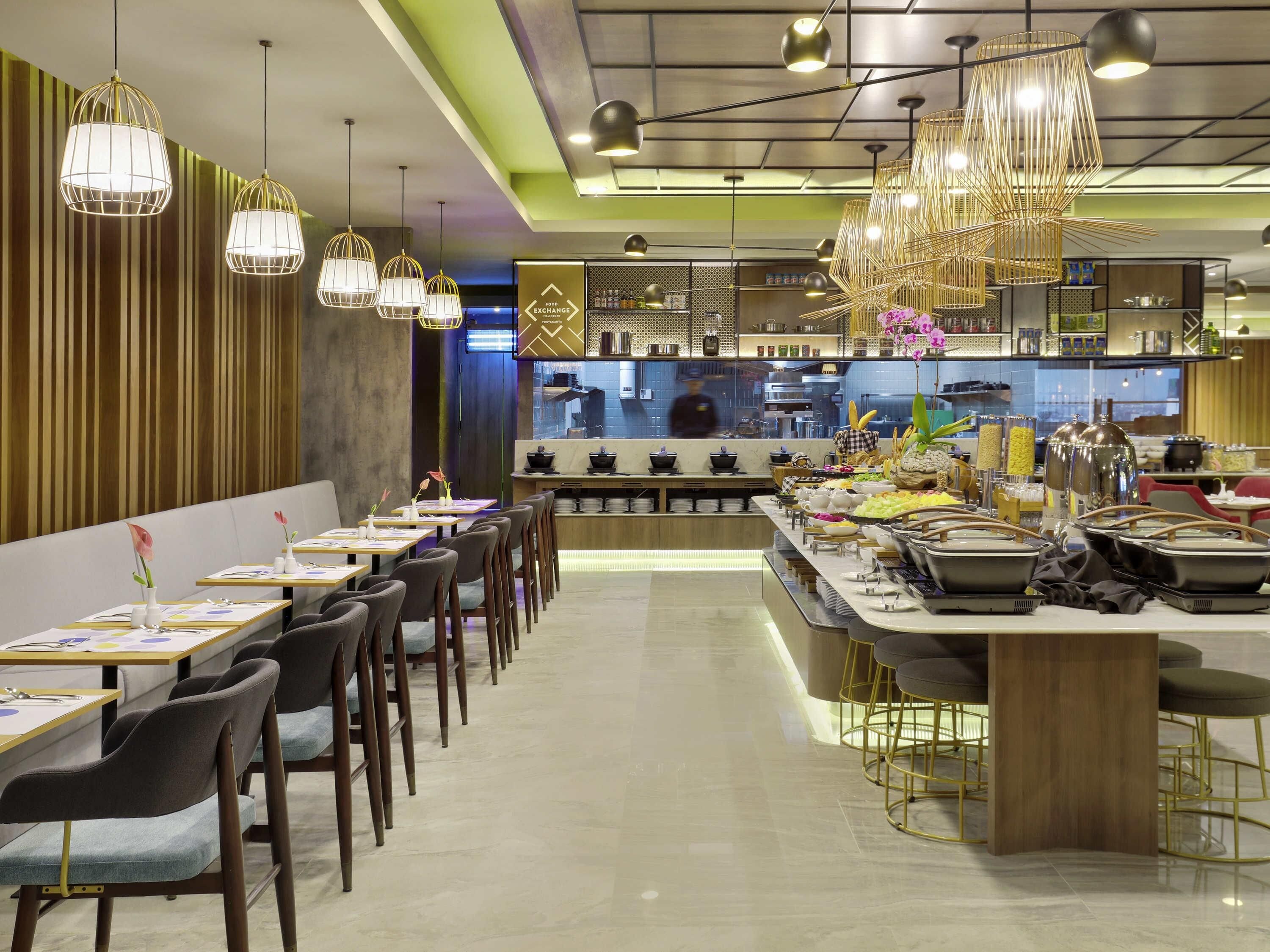 Un interior de restaurante moderno con un bufé, mesas para comer, sillas e iluminación colgante.