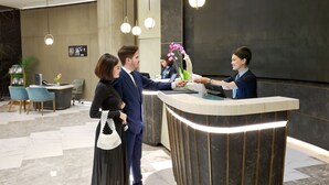 Ein Hotel-Empfangsbereich mit Marmorboden, einer Rezeption und einer Sitzecke mit Stühlen.