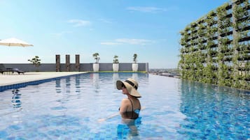 A swimming pool with clear blue water, surrounded by modern architecture and greenery.