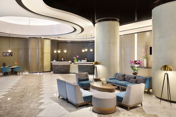 A modern lobby with a reception desk, seating area, and a large pillar. - Novotel Suites Yogyakarta Malioboro (Yogyakarta)
