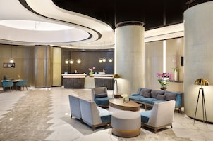 A modern lobby with a reception desk, seating area, and a large pillar.