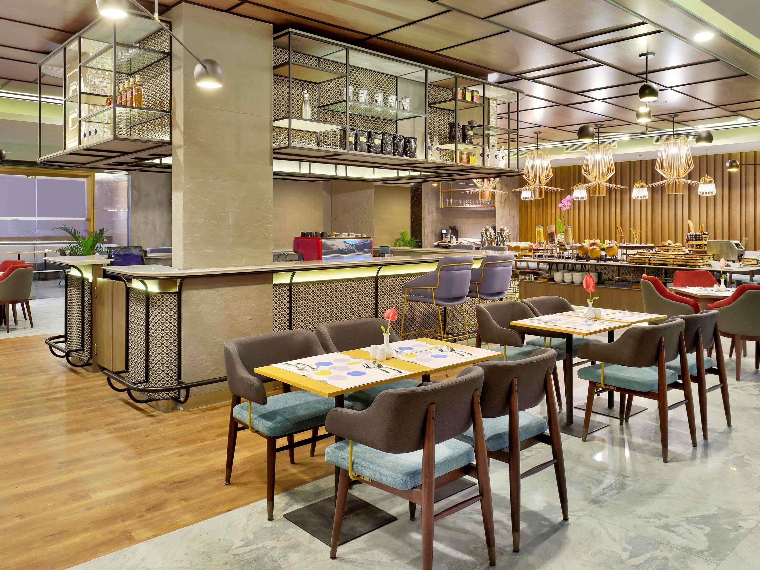 A modern restaurant with a bar area, seating with tables and chairs, and a patterned wall design.