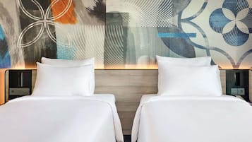 Una habitación de hotel con dos camas, un cuadro abstracto moderno en la pared y un cabecero de madera.