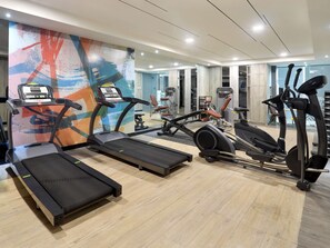 Une salle de sport équipée de tapis de course, de vélos elliptiques et de matériel de musculation.