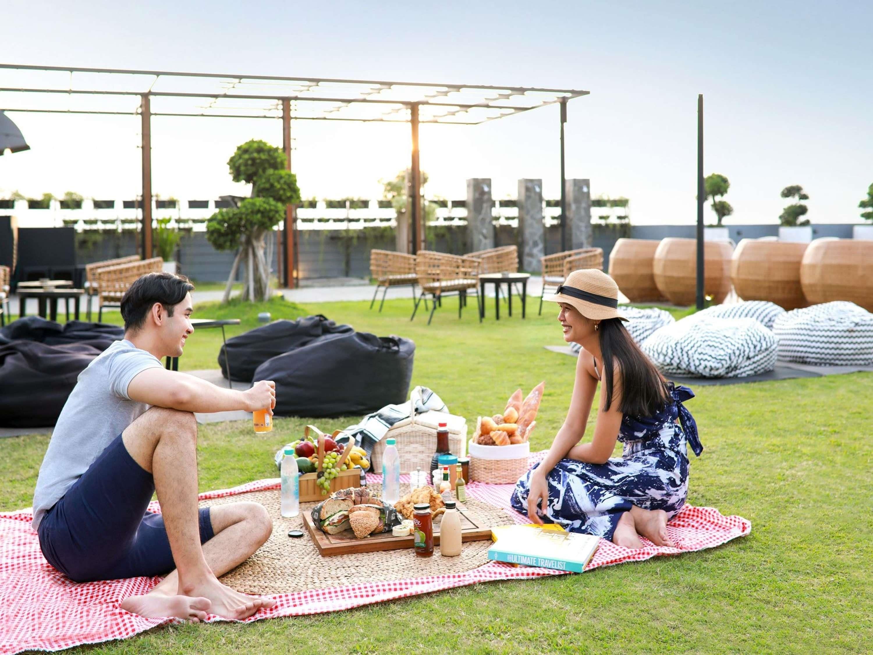 Un montaje para picnic sobre un césped, con una manta a cuadros, comida y bebidas.