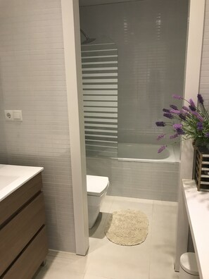 Un baño moderno con ducha, inodoro y tocador de madera.