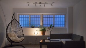 A living room with a hanging chair, a sofa, a coffee table, and a potted plant. - Kamelly Guest House (Badalona)