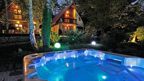 A hot tub in a garden with a house in the background. - 4 bedroom gorgeous home in Breze (Breze)