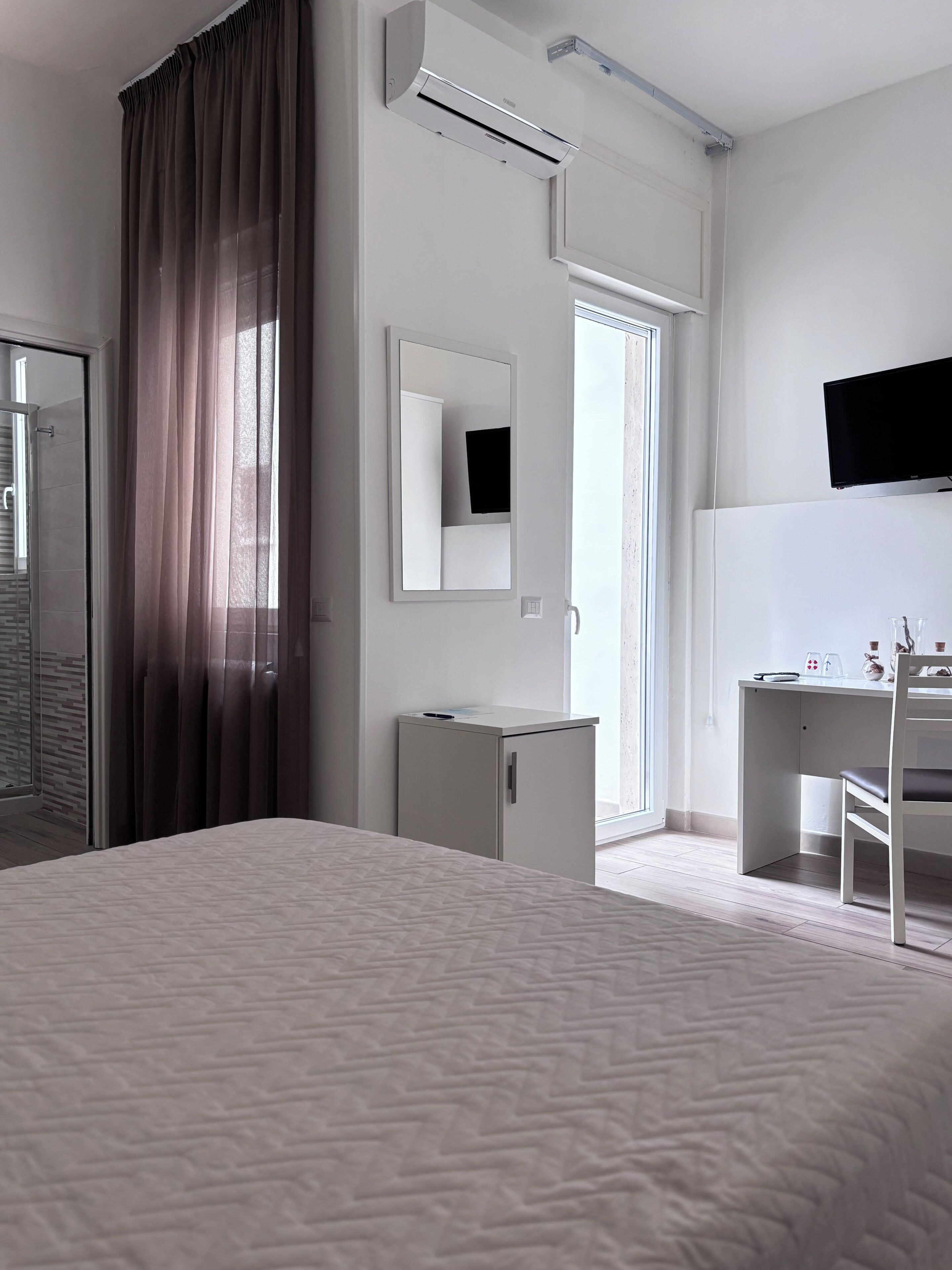 Une chambre d’hôtel équipée d’un lit, d’un bureau, d’une chaise, d’une télévision, d’une armoire et d’un miroir.