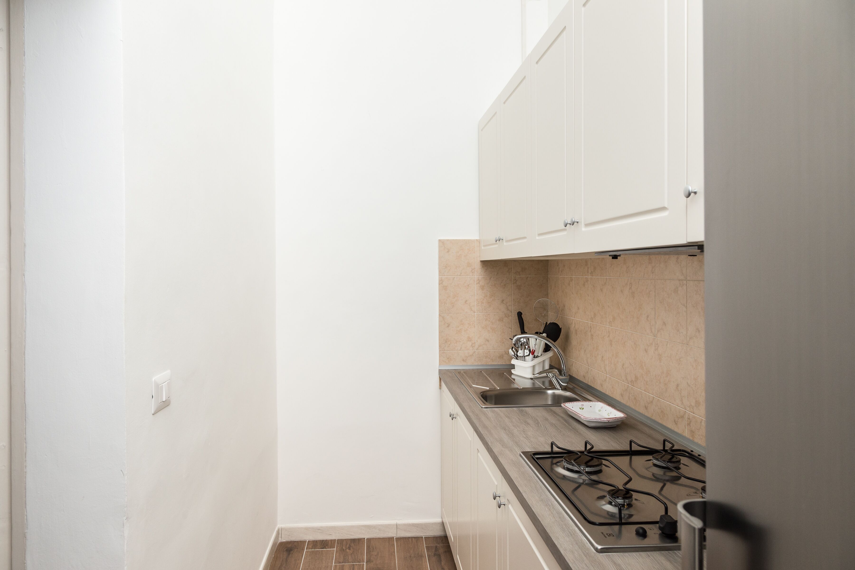 A small kitchen with white cabinets, a gas stove, and a sink.
