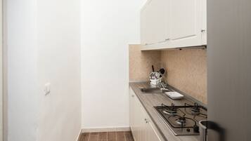 A small kitchen with white cabinets, a gas stove, and a sink.