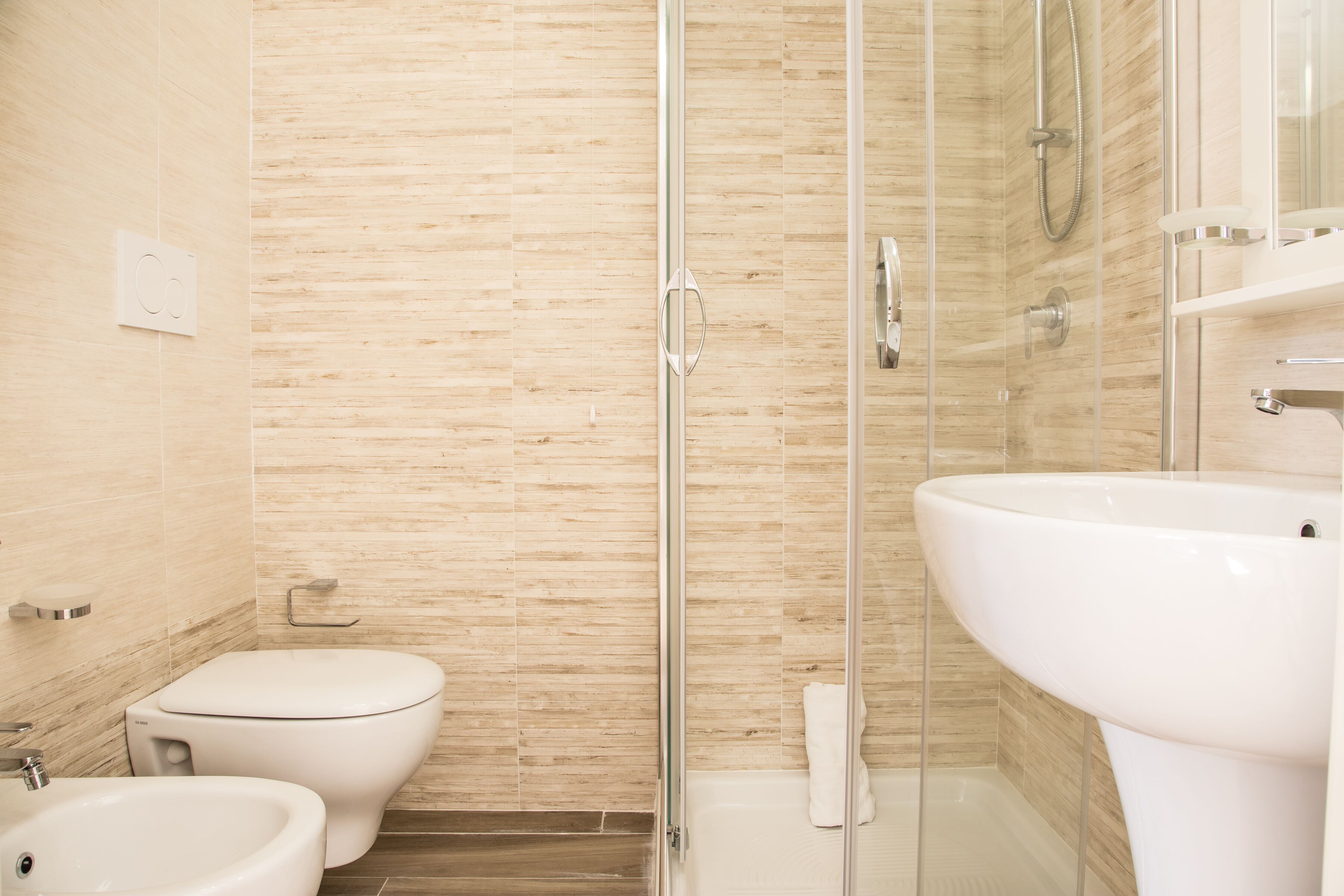 A modern bathroom with a glass shower enclosure, a toilet, and a sink.
