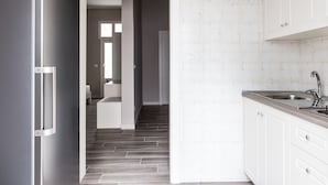 A modern kitchen with white cabinets, a stainless steel refrigerator, and a wooden floor. - Faro Bianco Gallipoli (Gallipoli)