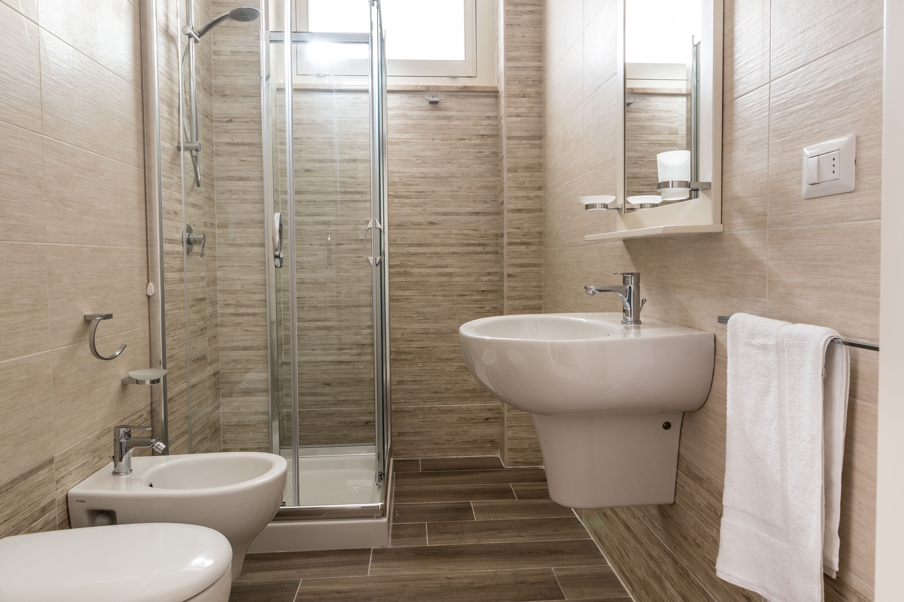 Un bagno moderno con doccia vetrata, un bidet e un lavandino.