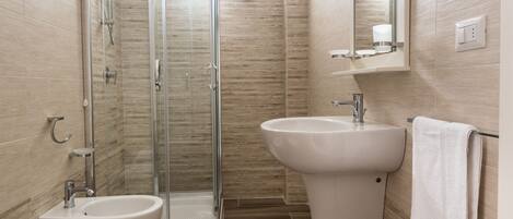 Un baño moderno con ducha de vidrio, un bidé y un lavamanos.