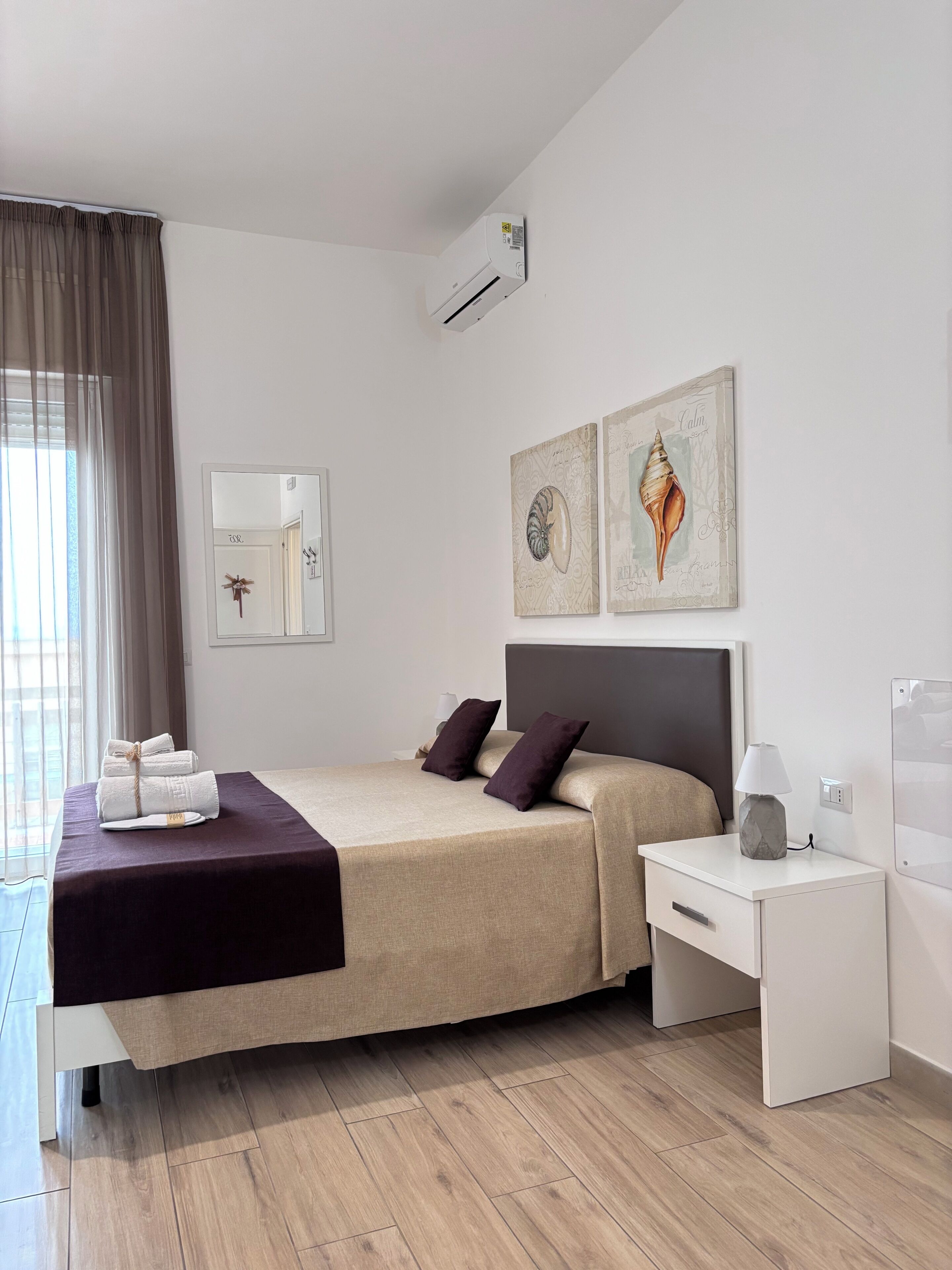 Una habitación de hotel moderna con cama, mesita de noche y una obra de arte en la pared.