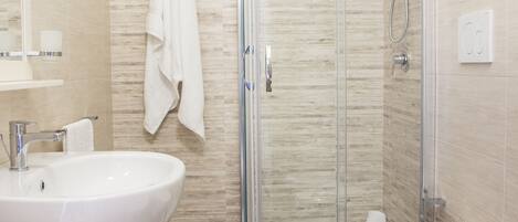 A modern bathroom with a glass-enclosed shower, two sinks, and a bidet.
