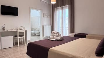 Una habitación de hotel con cama, escritorio, silla y televisor instalado en la pared.