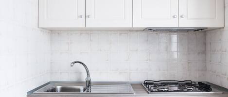 A kitchen with white cabinets, a stainless steel sink, and a gas stove.