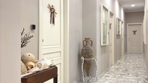 A hallway with marble flooring, white doors, and a small table with decorative items. - Faro Bianco Gallipoli (Gallipoli)