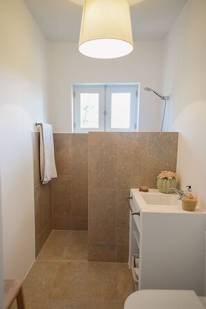 Un baño con ducha, lavamanos y ventana.
