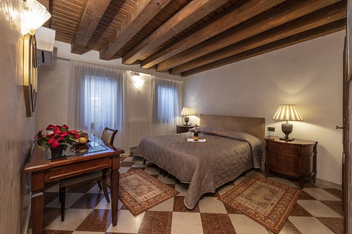 Un dormitorio con cama, mesitas de noche, escritorio y silla.