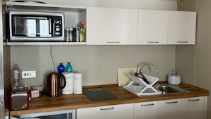 A compact kitchenette with a microwave, kettle, toaster, and a sink with a dish rack. - Anzolo Palace (Venice)