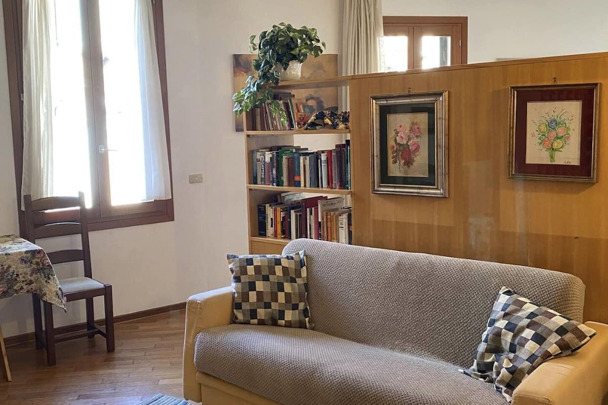 Una sala de estar acogedora con un sofá, una estantería y un comedor con mesa y sillas.
