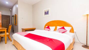 A neatly arranged hotel room with a large bed, a wooden nightstand, a chair, and a desk.