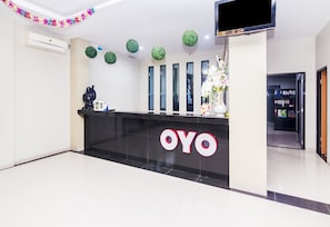 A reception desk with a black counter and the logo 'OYO' in white letters. - Capital O 1867 Kara Guest House (Batam)