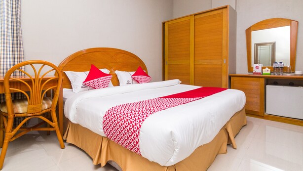 Una camera d'albergo con un letto, un armadio, una scrivania e uno specchio, tutti in legno.