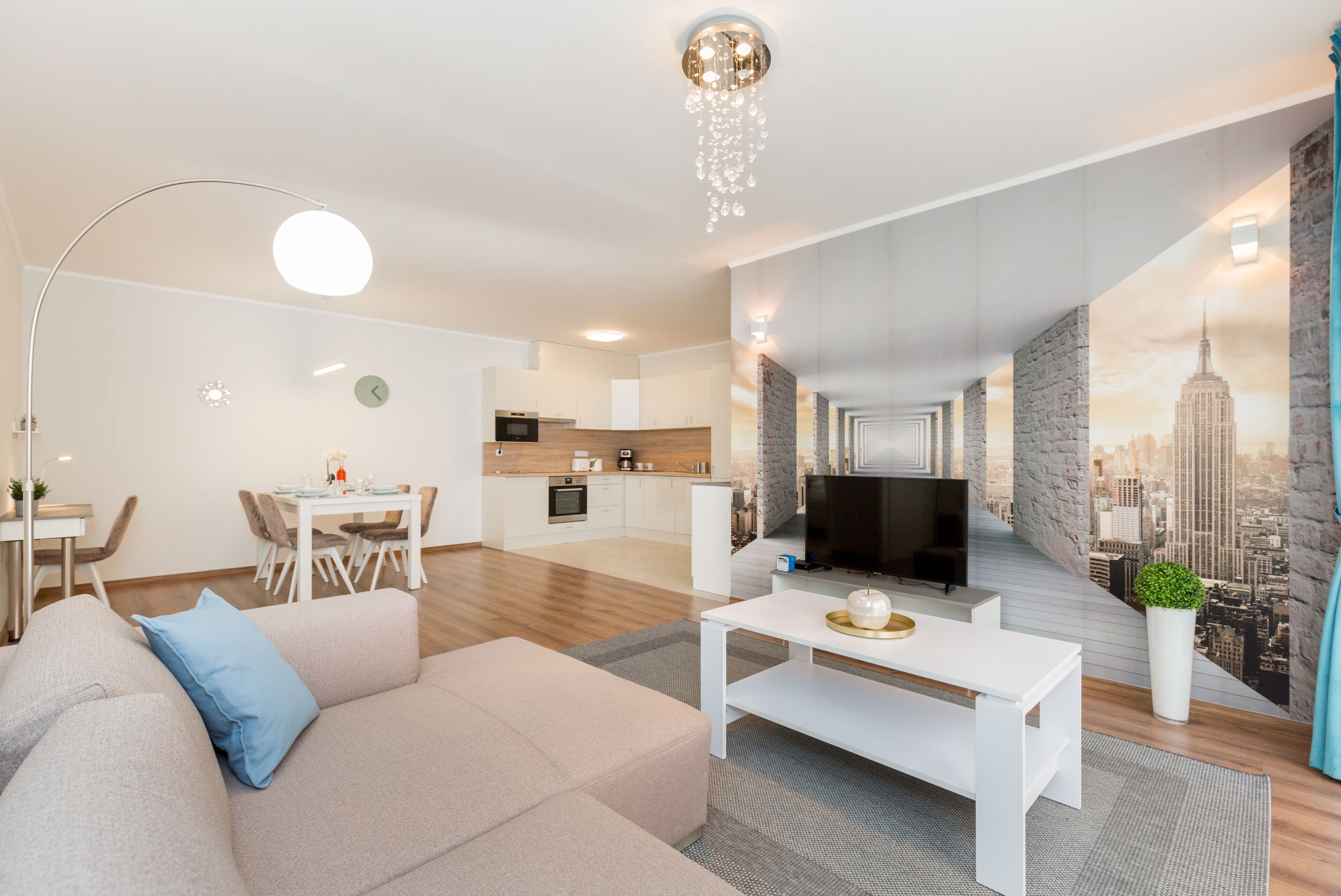 A modern living room with a sofa, coffee table, and a cityscape mural on the wall.