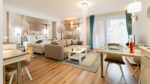 A modern living room with a sofa, coffee table, dining table, and a chandelier. - Budapest Downtown Residence (Budapest)