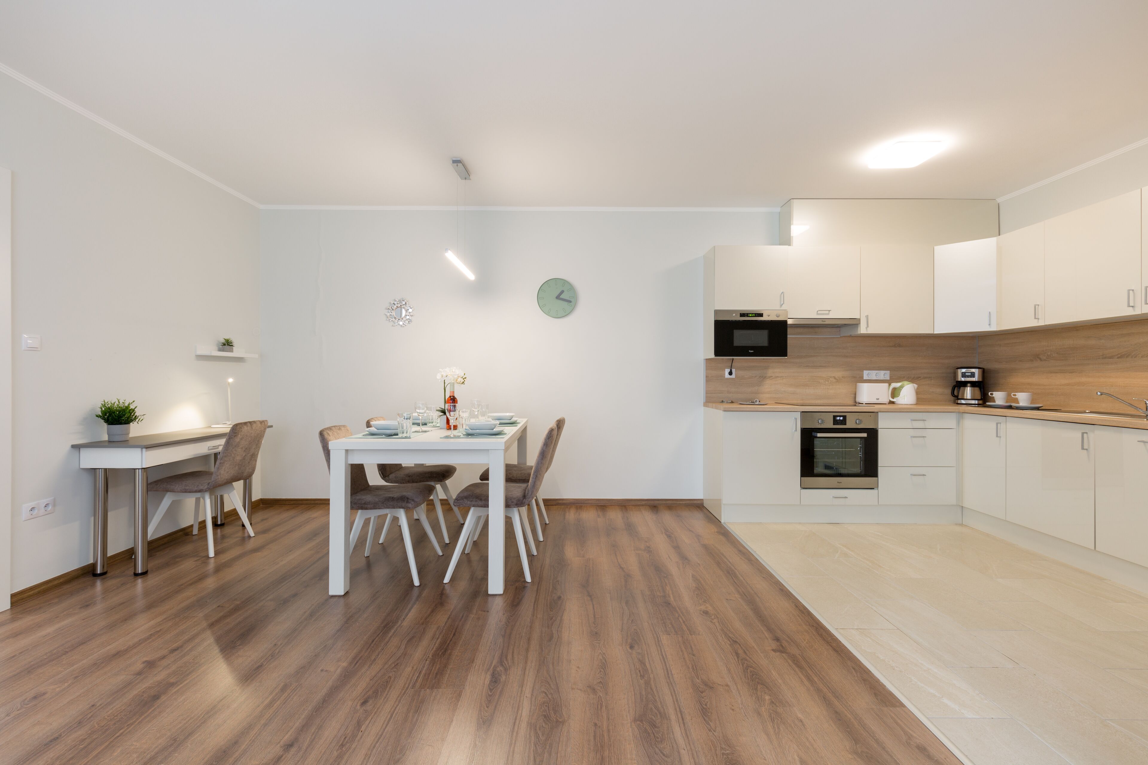 A modern kitchen with white cabinets, a wooden countertop, and a built-in oven.