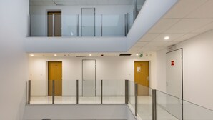 A modern indoor space with a glass railing, multiple doors, and a clean, tiled floor. - Budapest Downtown Residence (Budapest)
