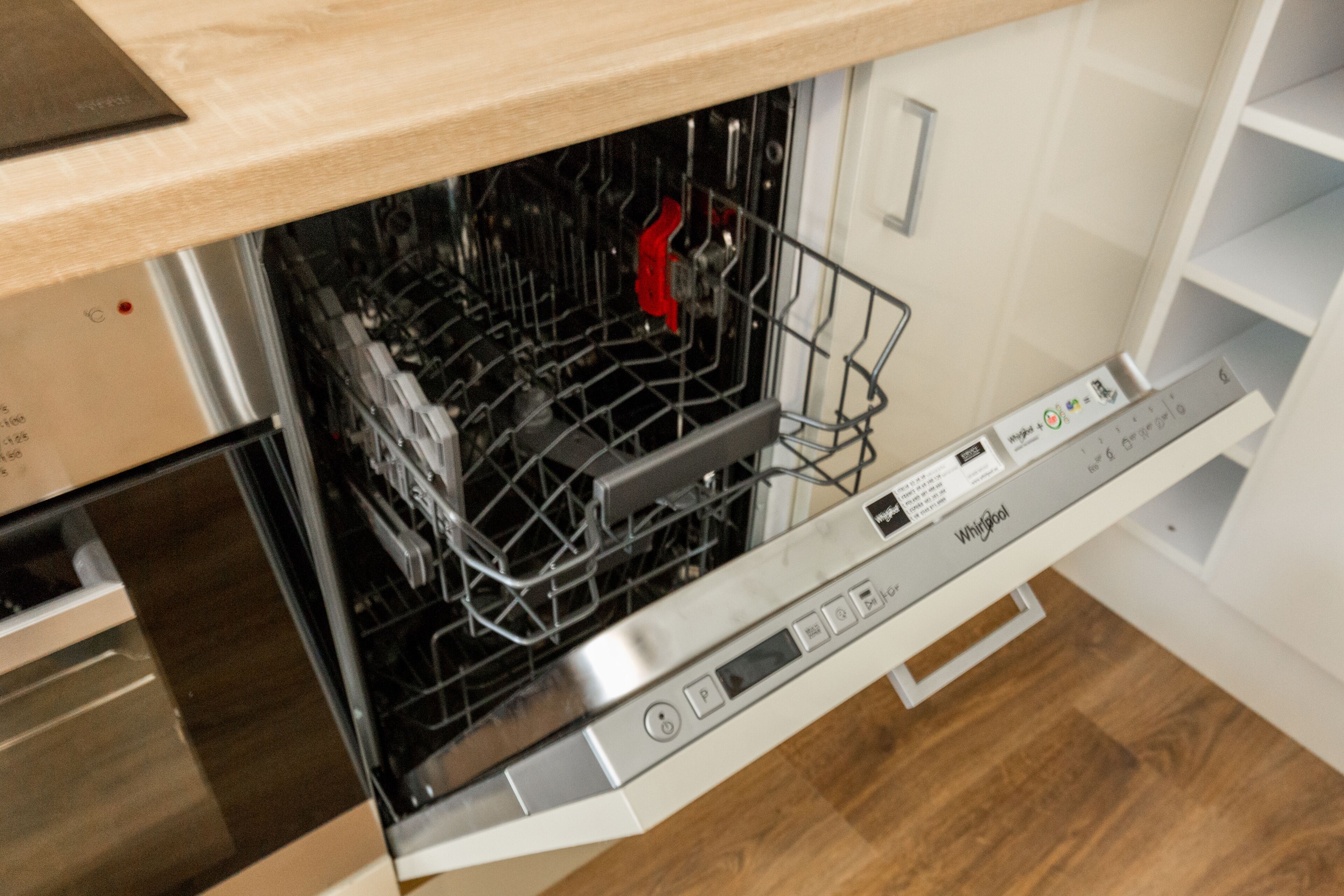 Una cocina moderna con lavavajillas, horno empotrado y encimera de madera.